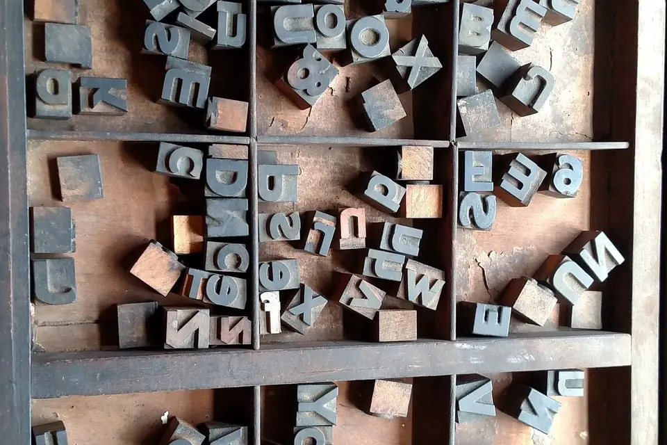 A wooden printer's type case full of metal type pieces for the Cherokee syllabary, scattered in its compartments