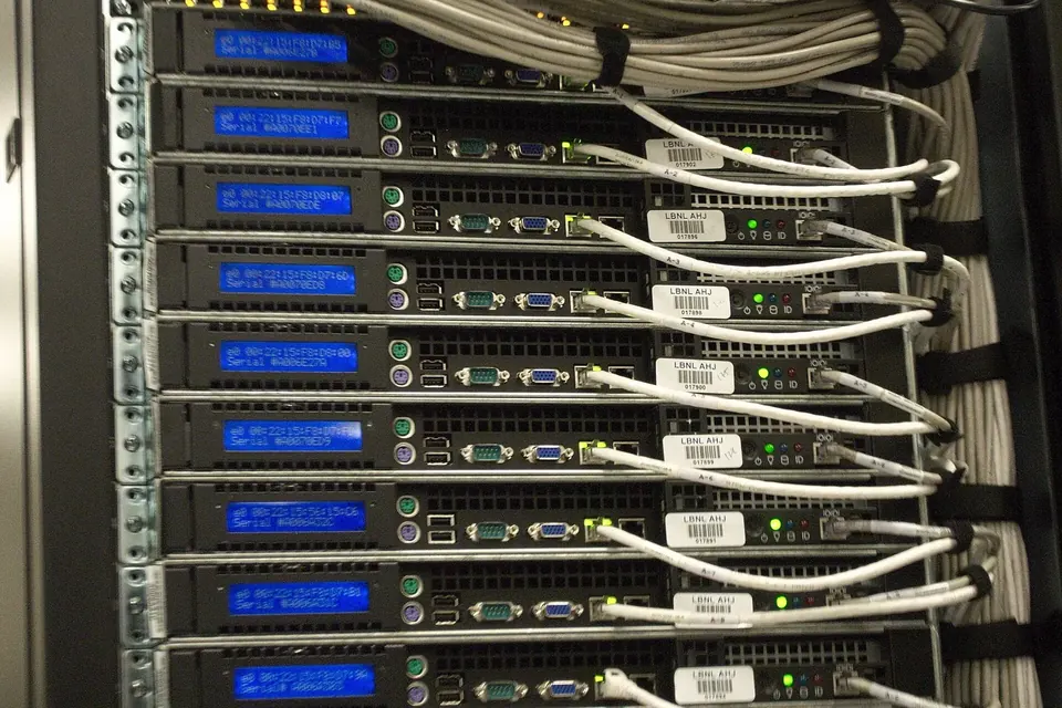 A server rack packed with stacked machines, blue status displays and bundles of white network cables